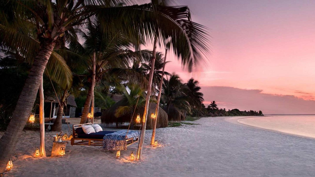 Beachfront resort bungalows with palm trees on a calm West African beach at sunset