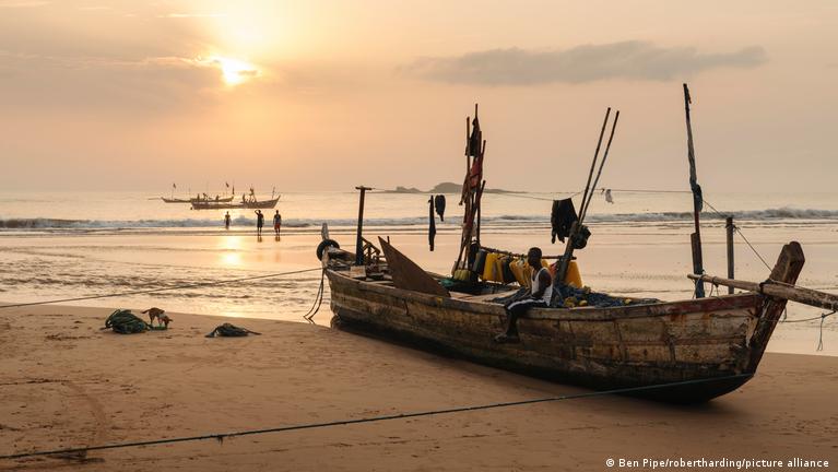 Local fishermen on a wooden boat near a Liberian beach village at sunrise