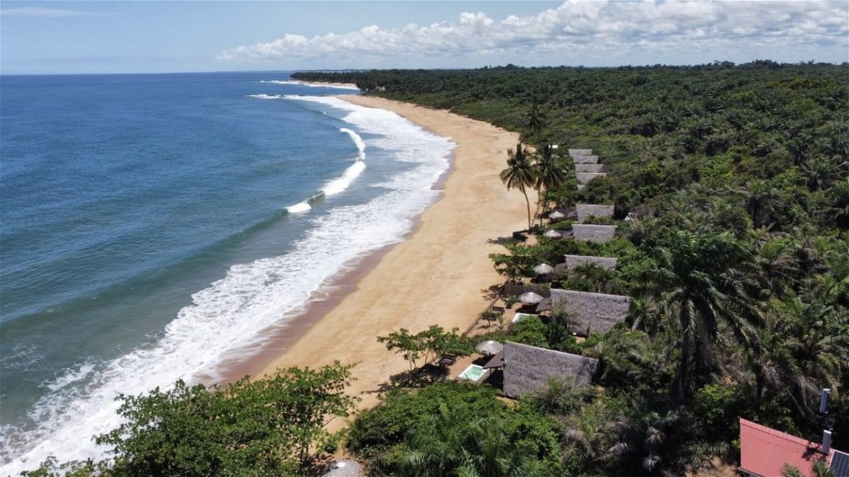Wide empty beach in Liberia with Atlantic waves and tropical forest backdrop