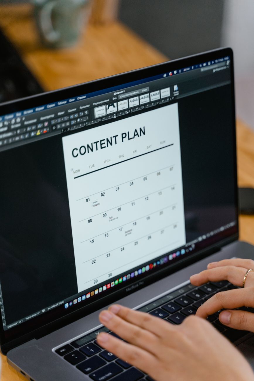 Social media content calendar with color-coded post types on a laptop screen