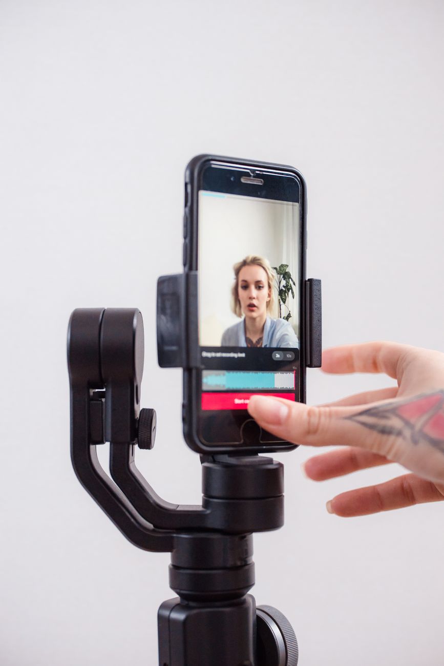Person filming short form video on smartphone with ring light