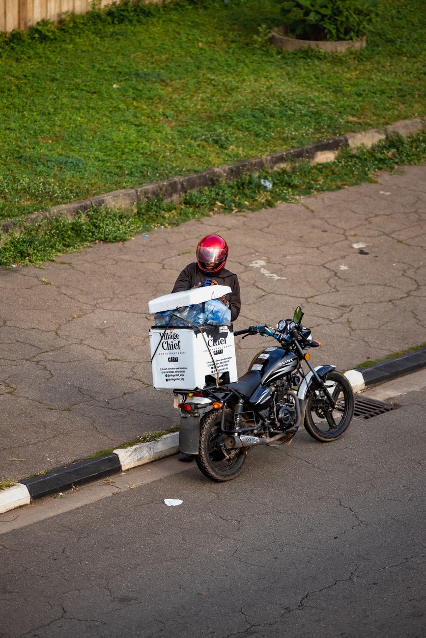 Motorcycle delivery rider in African city navigating urban traffic
