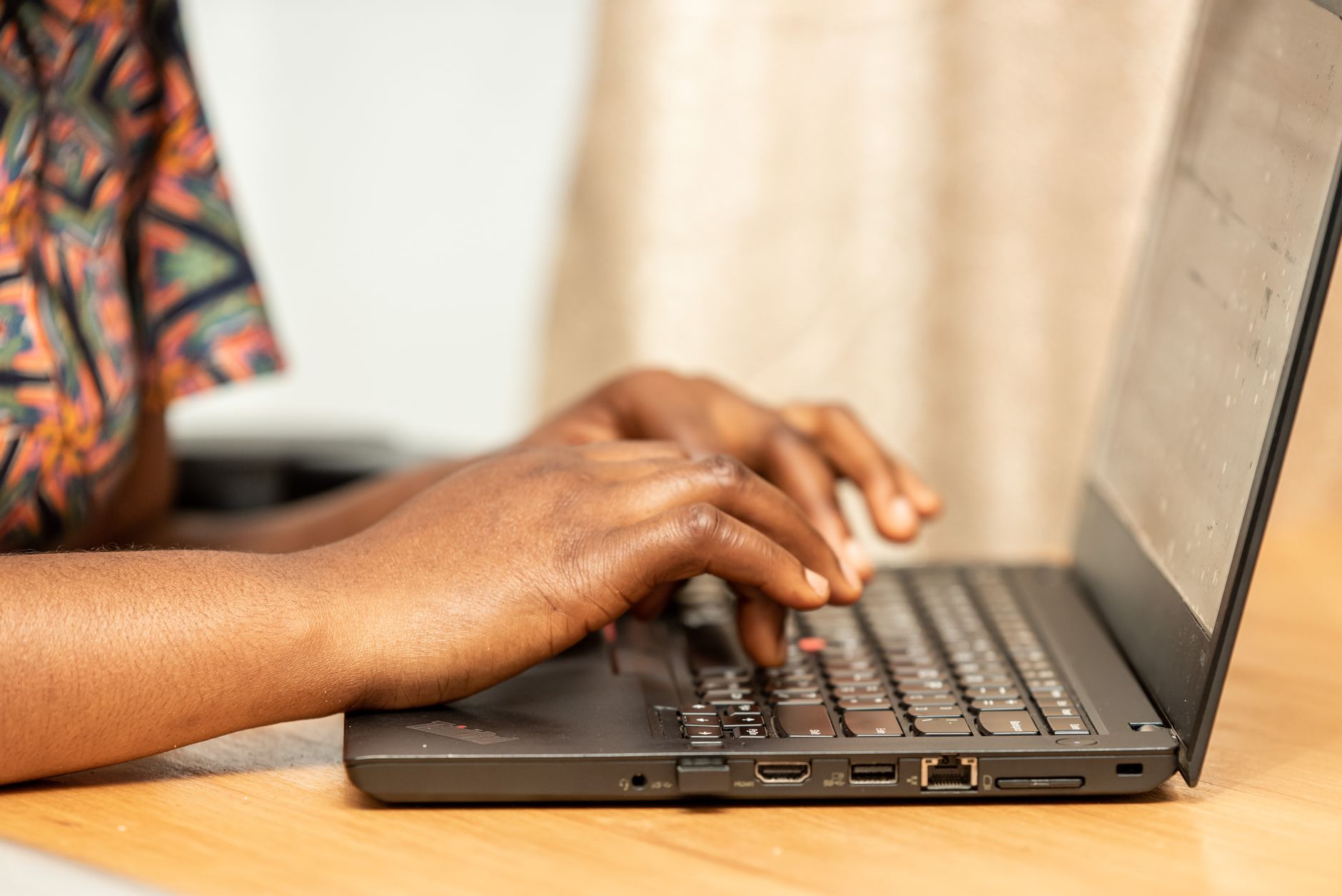 African tech entrepreneur working on laptop with data charts on screen