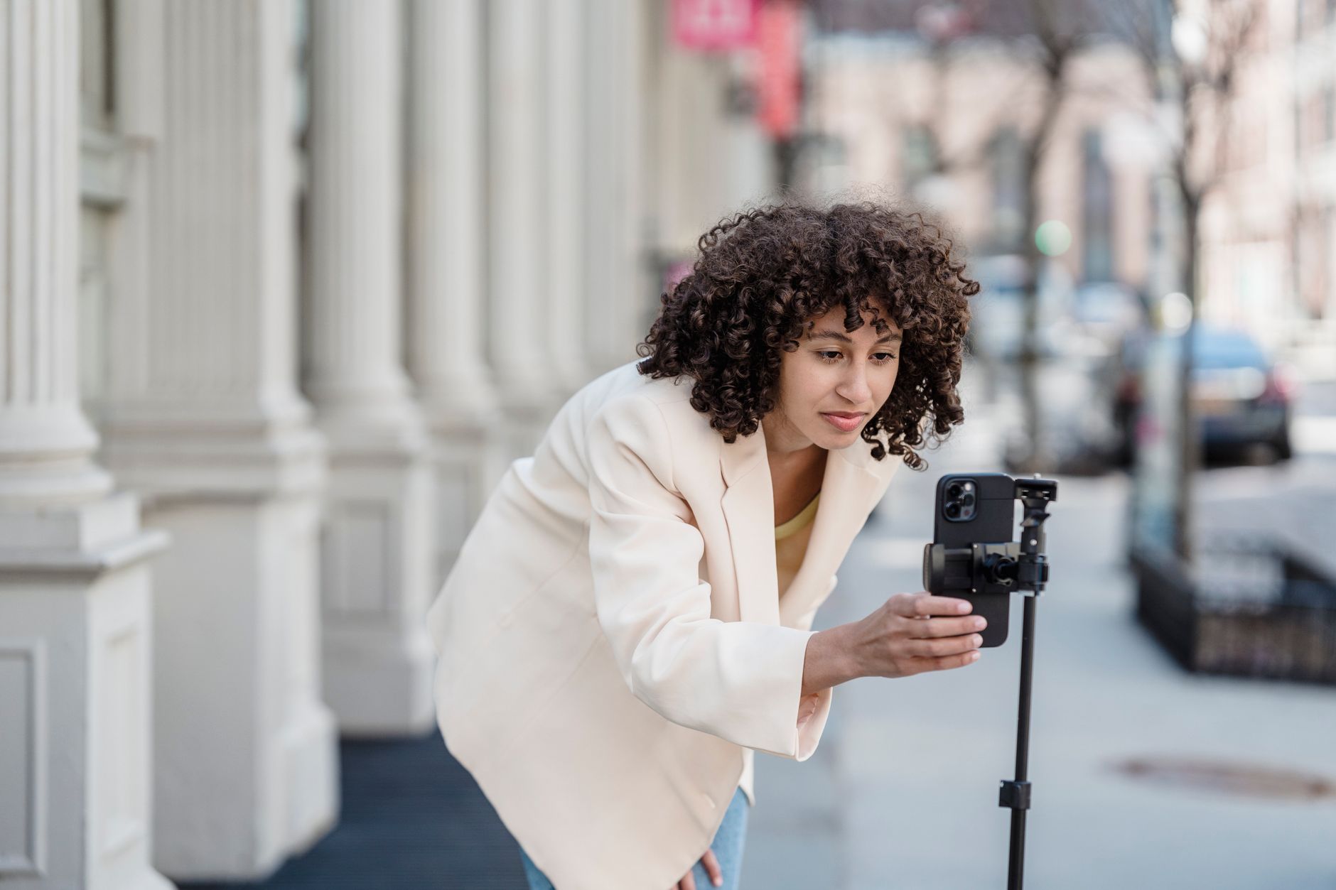 African creator filming content on a smartphone in a vibrant urban setting