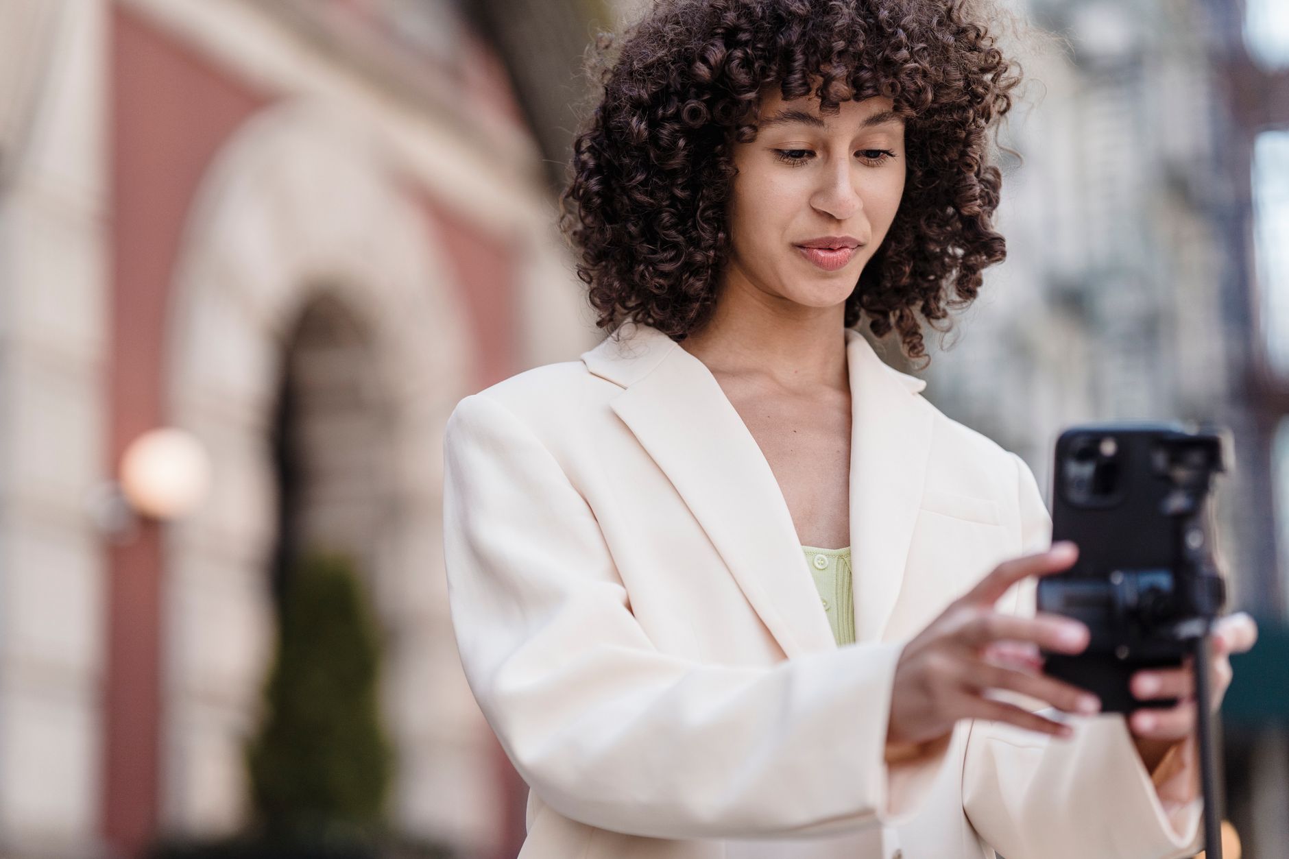 African content creator filming a video on a smartphone in a vibrant urban setting