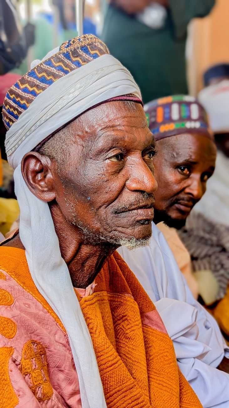 African elders sitting in a circle engaged in community discussion under a tree