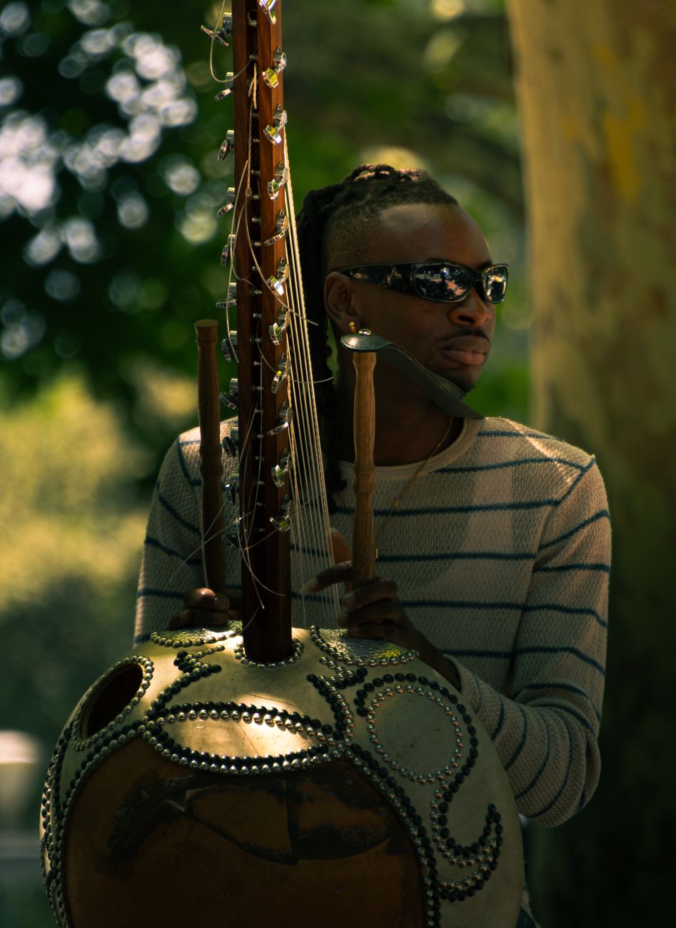 West African griot playing a kora instrument outdoors