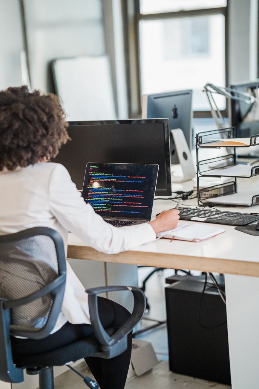 African woman developer coding on laptop with data visualisation on screen