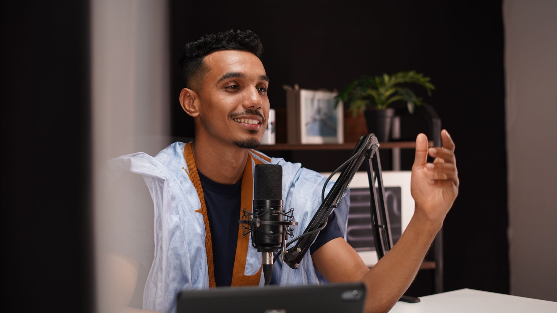 African podcaster recording in a home studio with microphone and headphones