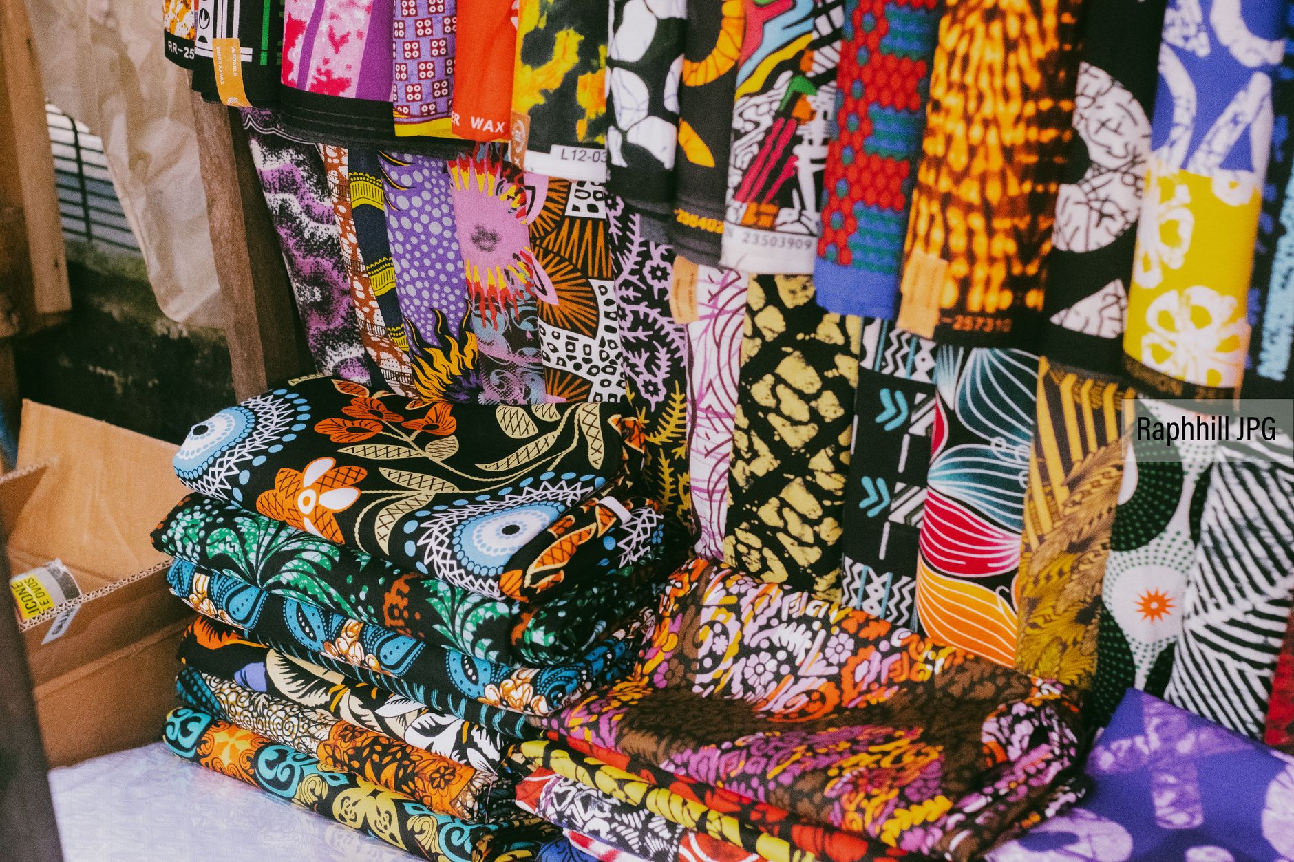 African fashion designer working with traditional textiles in a studio