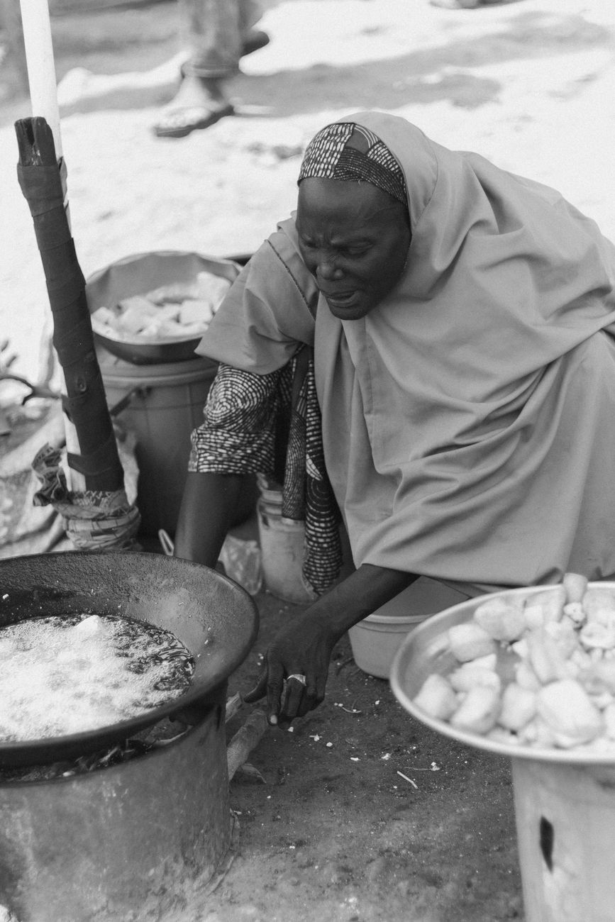 African woman preparing traditional jollof rice dish with colorful spices and ingredients