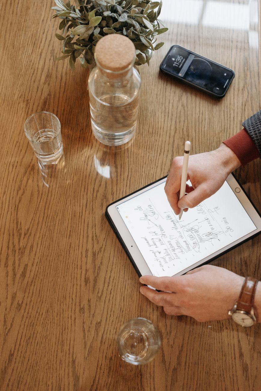 Person using a Bible study app on tablet with open notebook for scripture notes