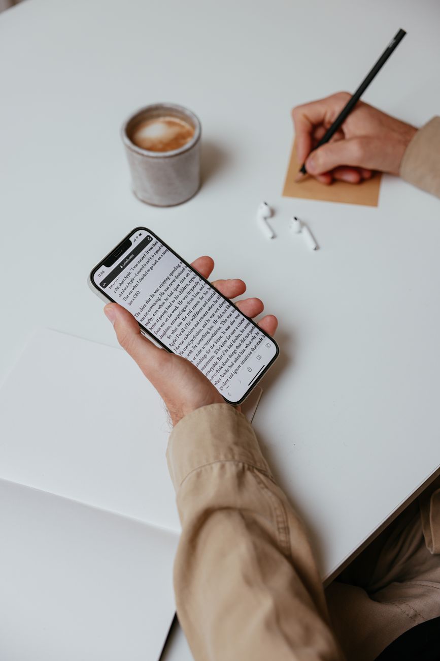 Person reading a difficult Bible passage on a smartphone with a notepad nearby