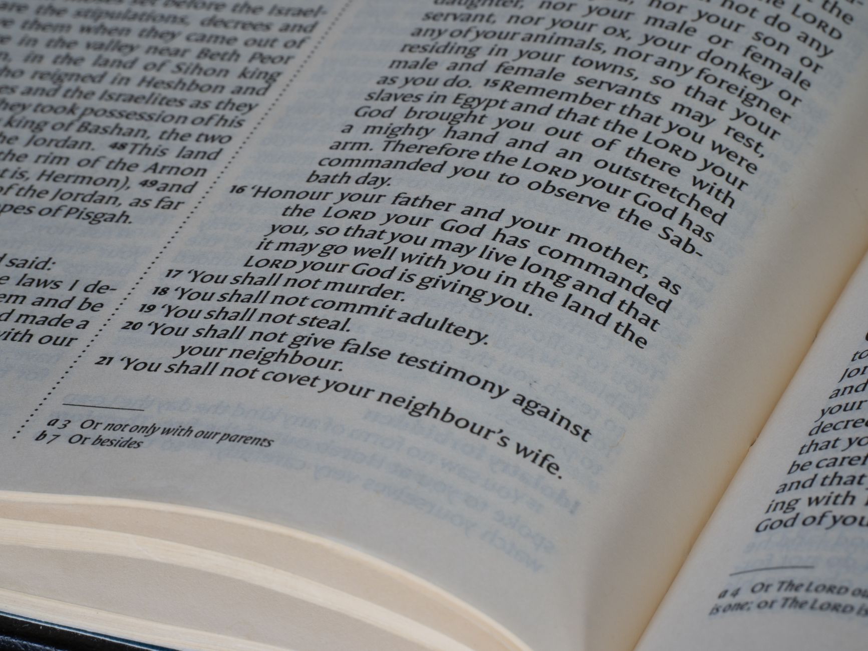 Open Bible with multiple translation bookmarks and a smartphone showing a Bible app