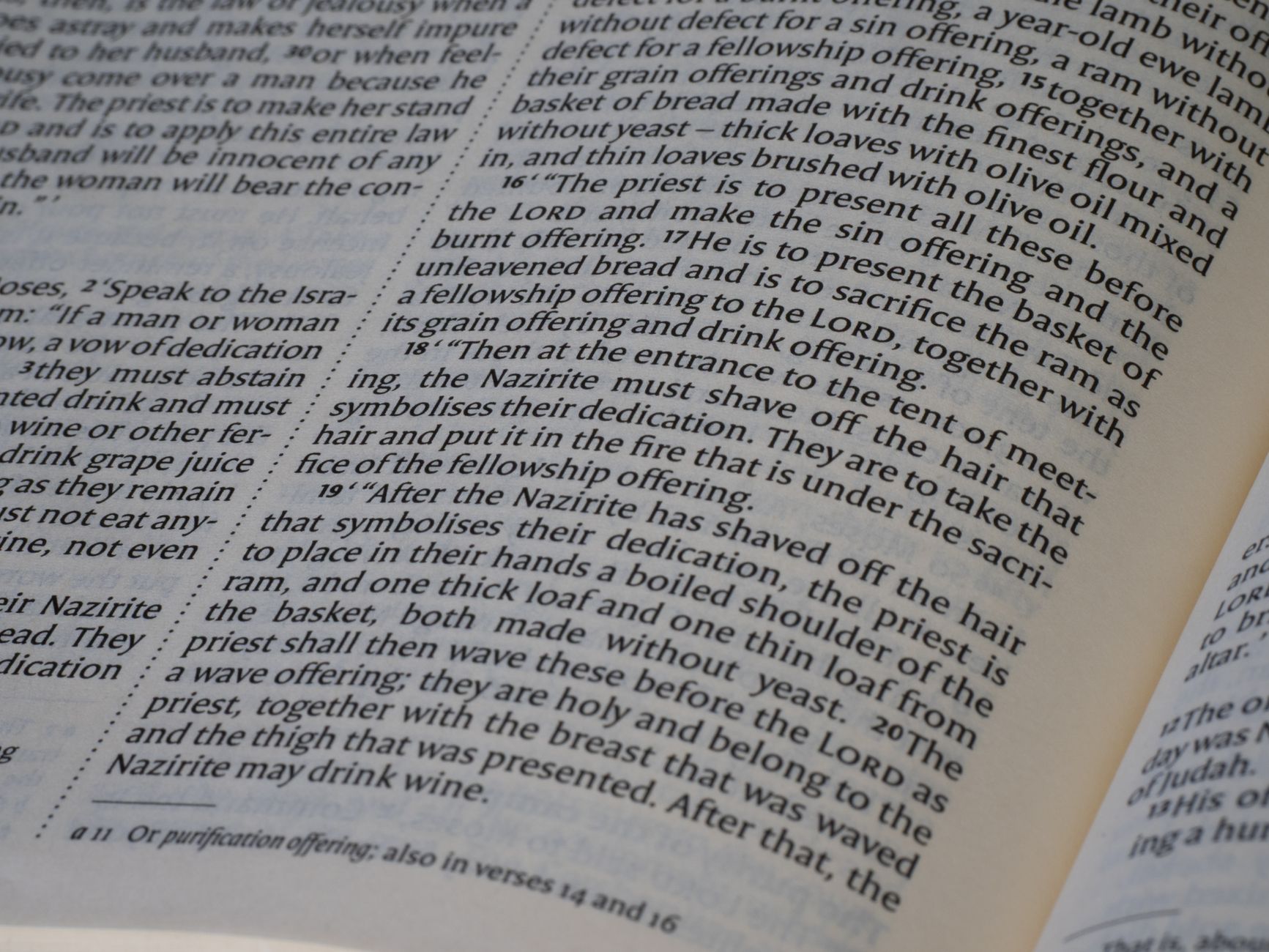 Open ancient Bible manuscript on a wooden desk with a magnifying glass