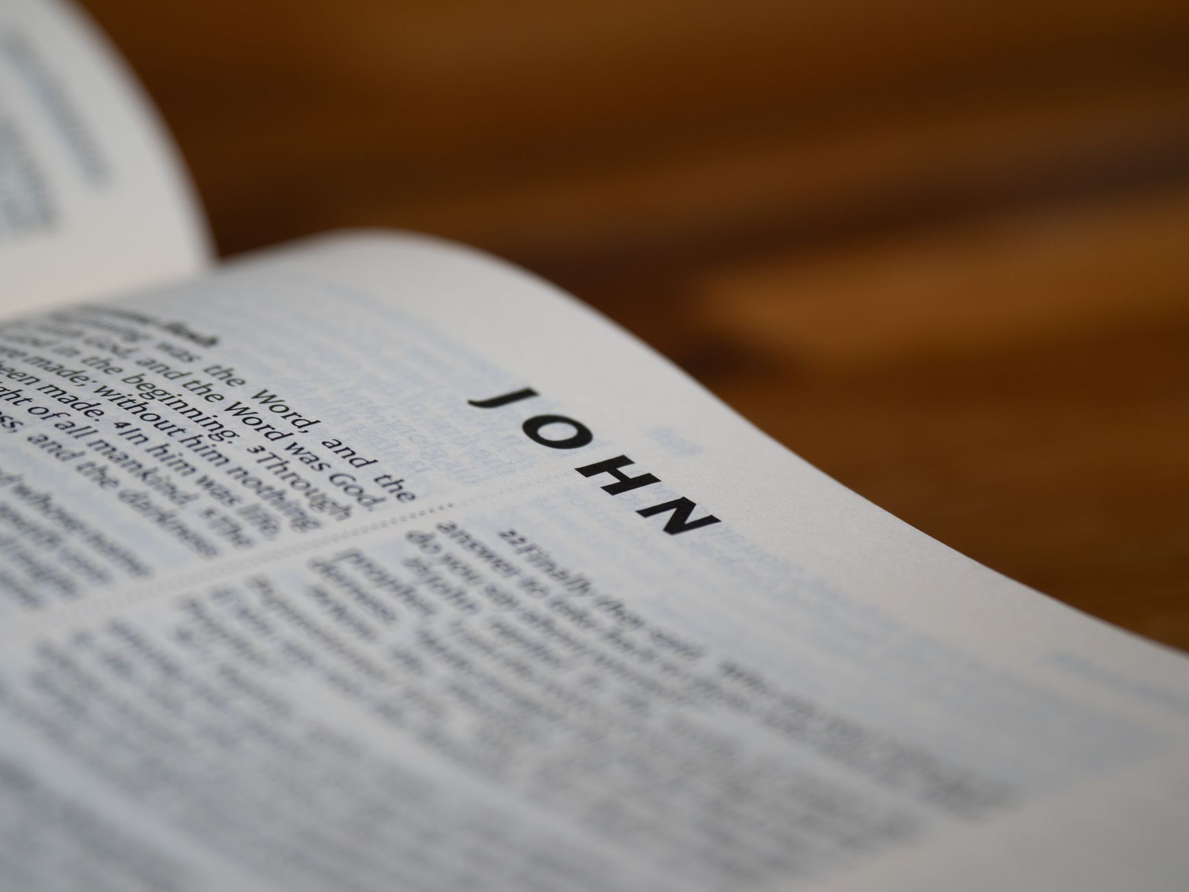 Gospel of John open on a wooden table with reading glasses