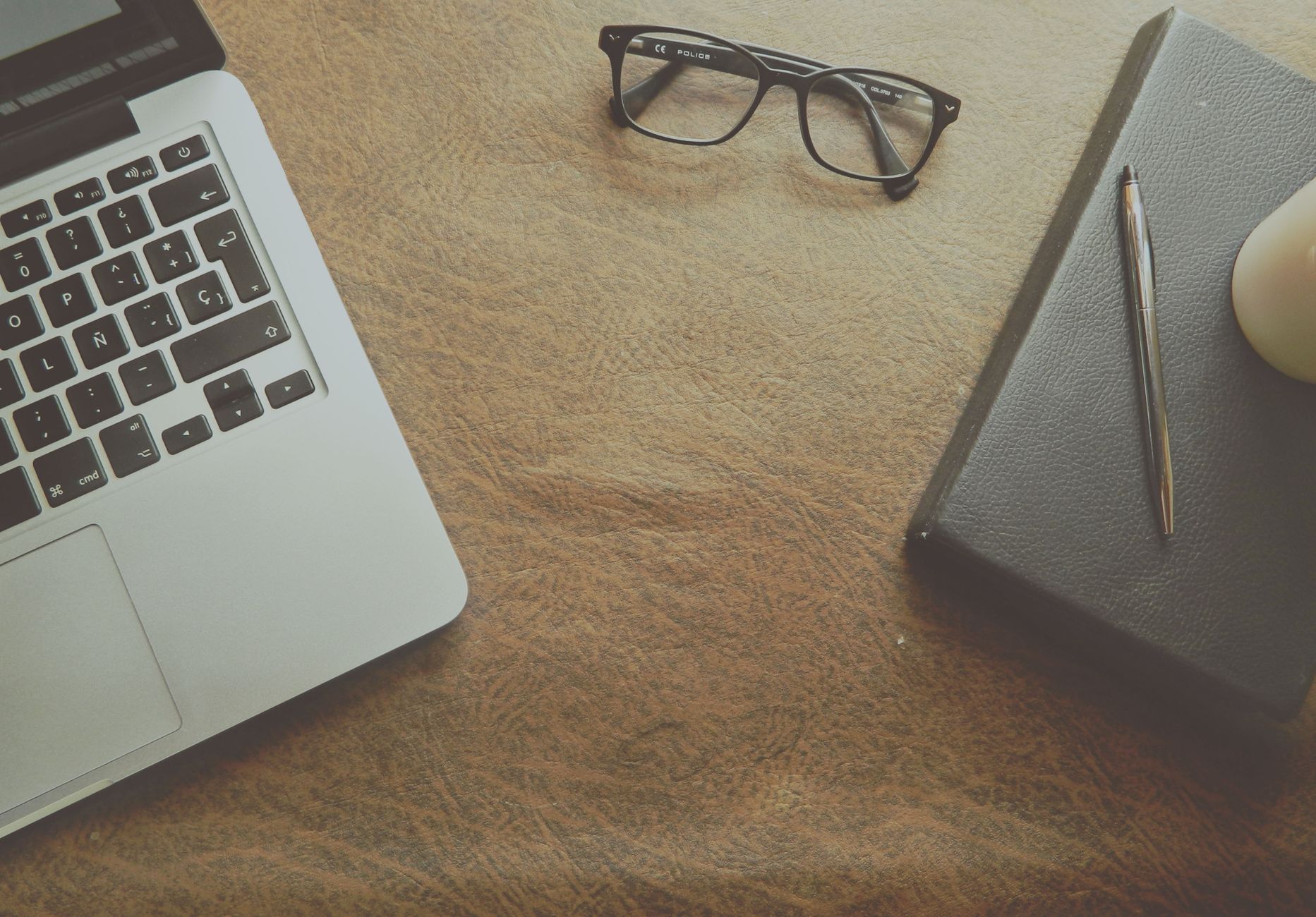 Person studying Bible with laptop and notebook open on a wooden desk