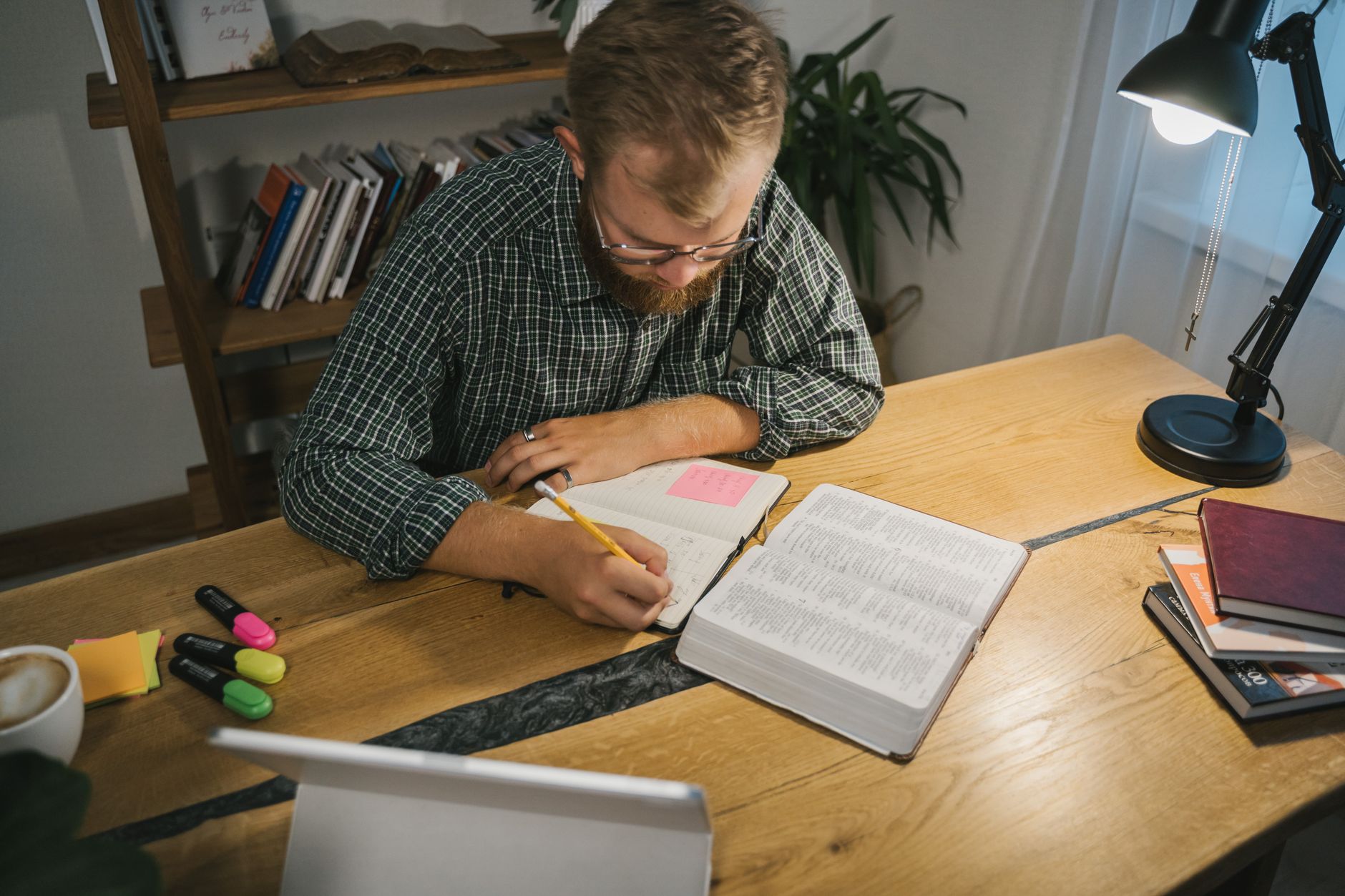 Open Bible with highlighted verses and study notes on a wooden desk
