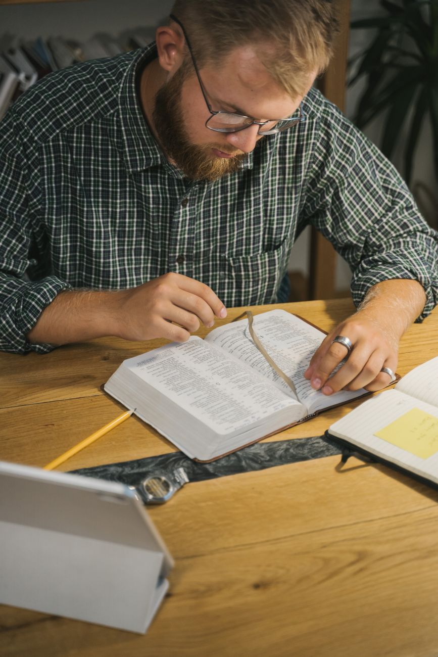 Person studying multiple Bible versions on a tablet and phone