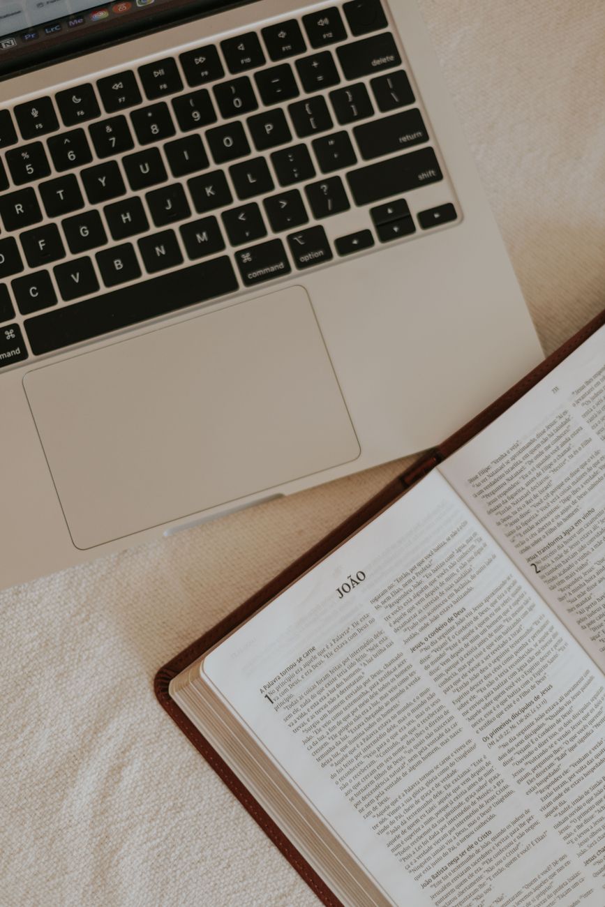 Open Bible with highlighted verses and study notes beside a laptop