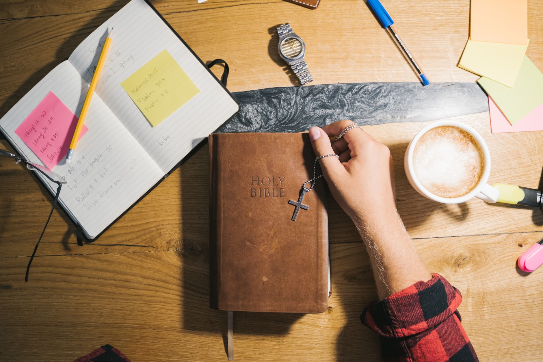 Person reading the Bible at a desk with a notebook and coffee