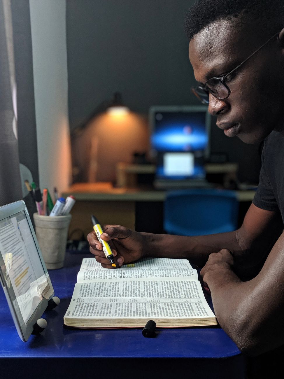 Person reading a Christian study guide alongside a Bible app on a tablet