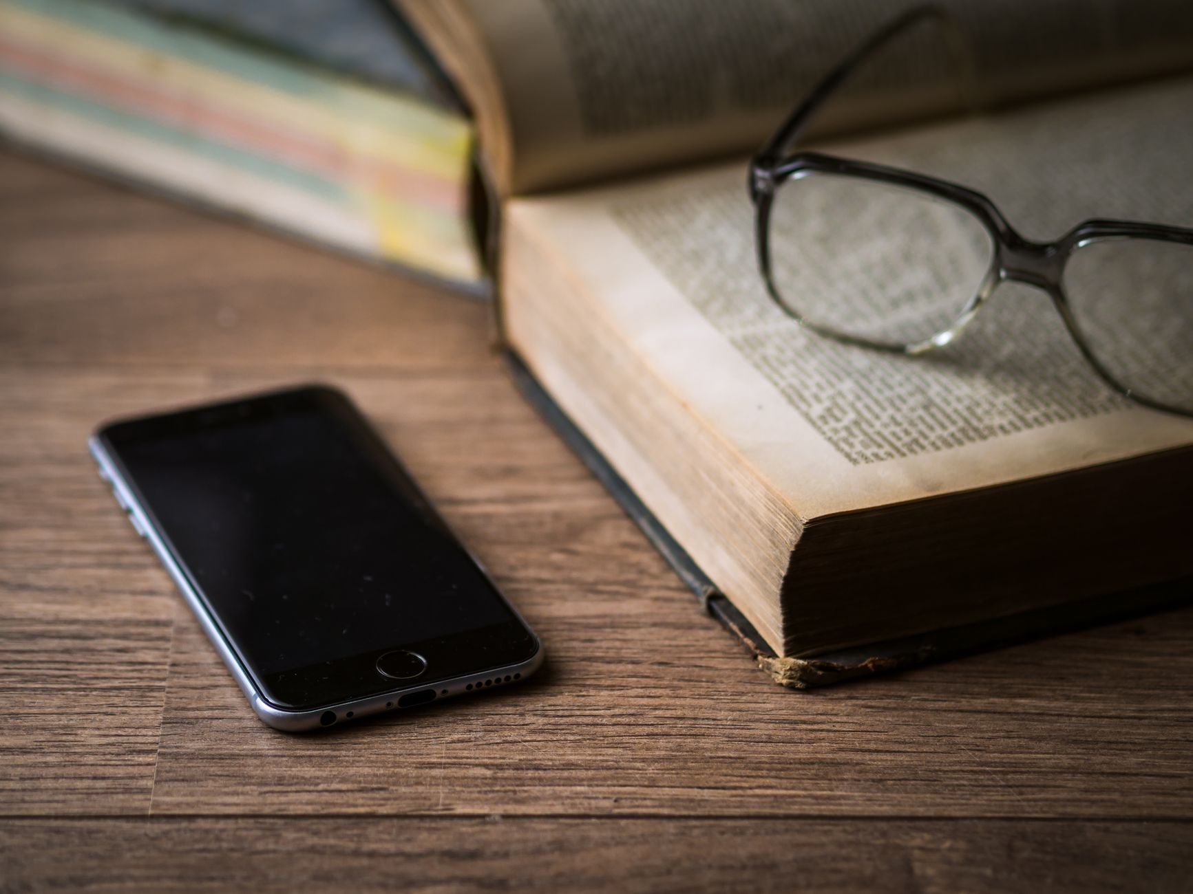 Person studying the Bible on a smartphone with notes and coffee on a desk