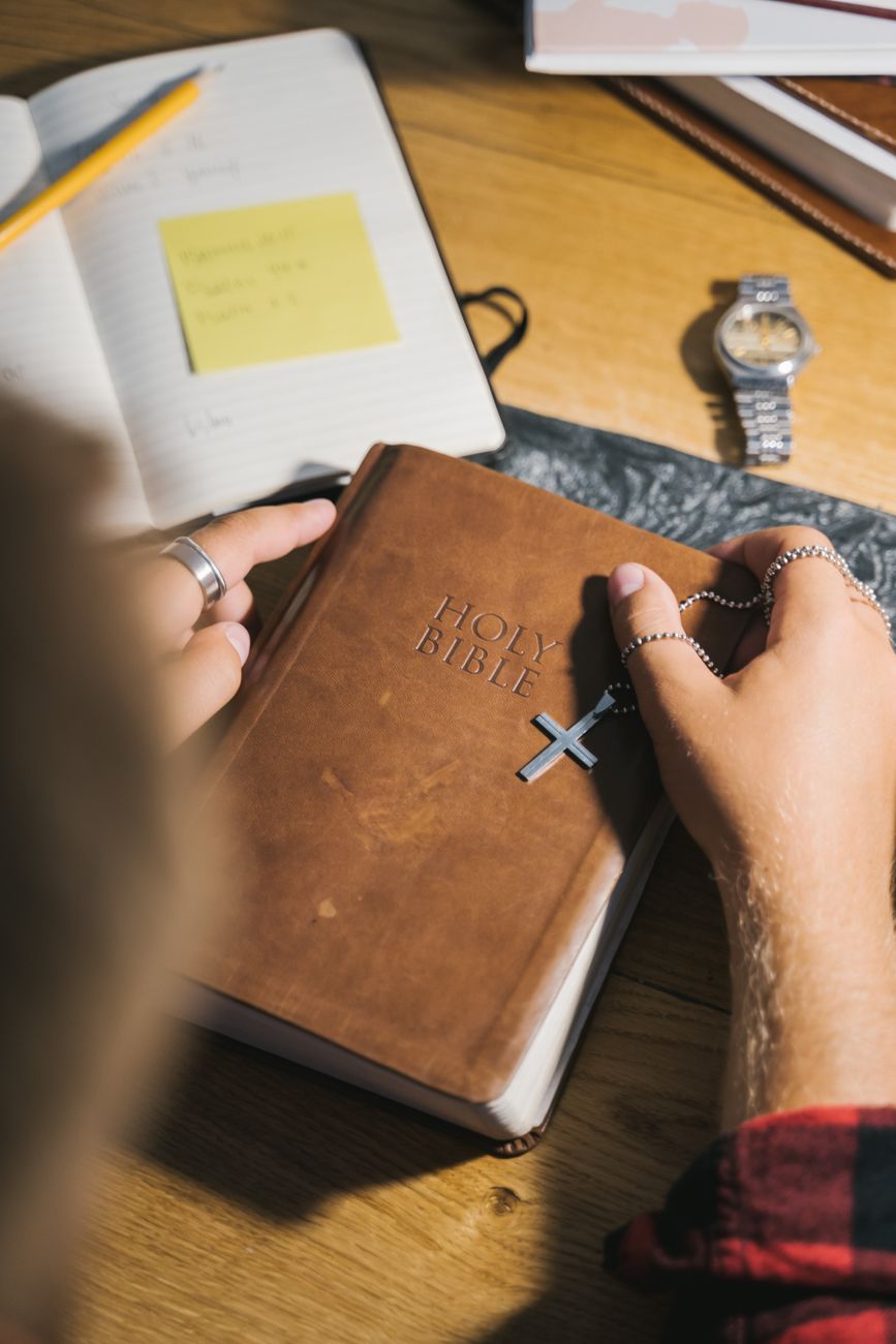 Open Bible next to smartphone and headphones on a wooden desk
