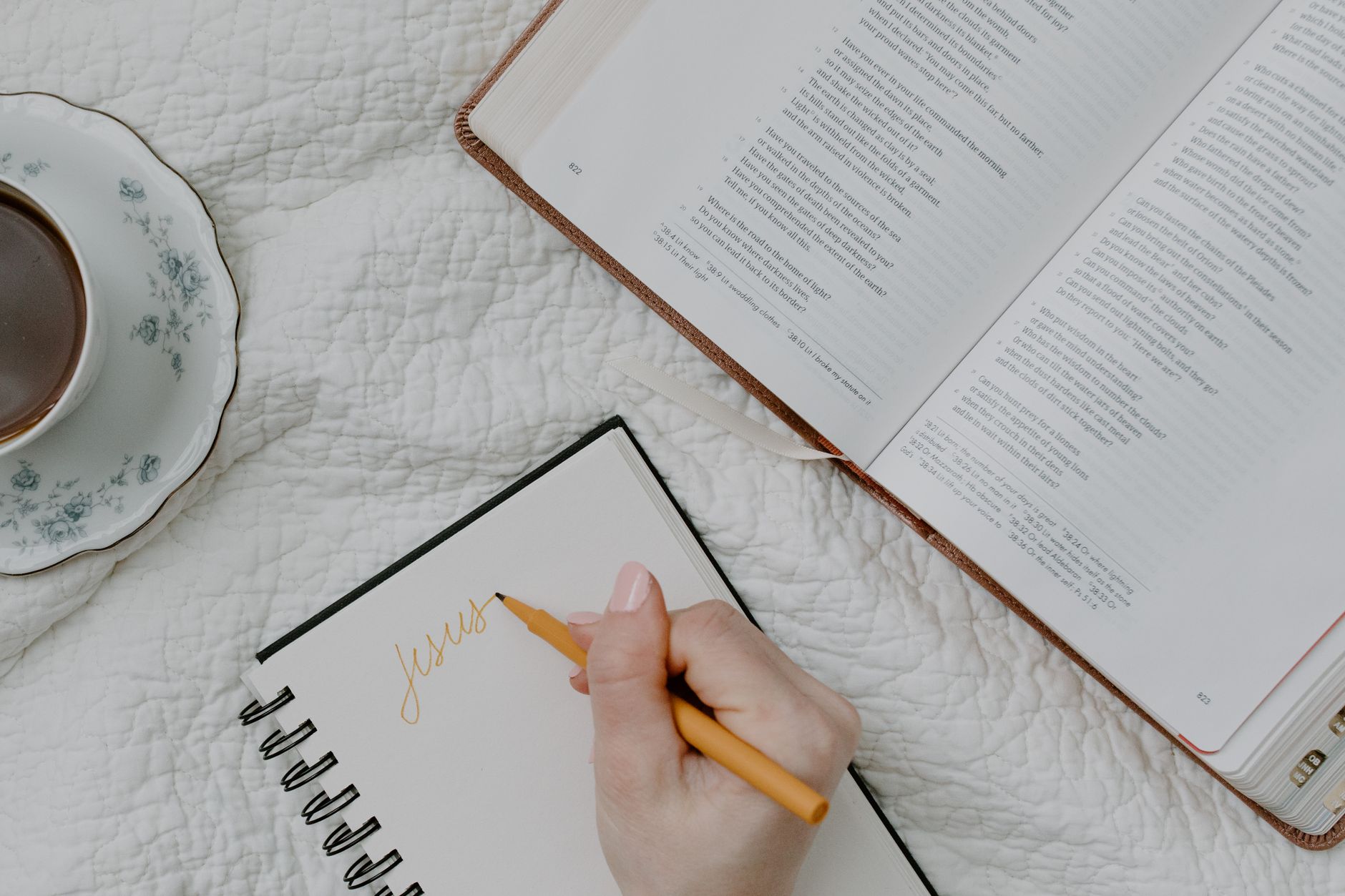 Woman studying Bible with tablet and journal on a cozy desk