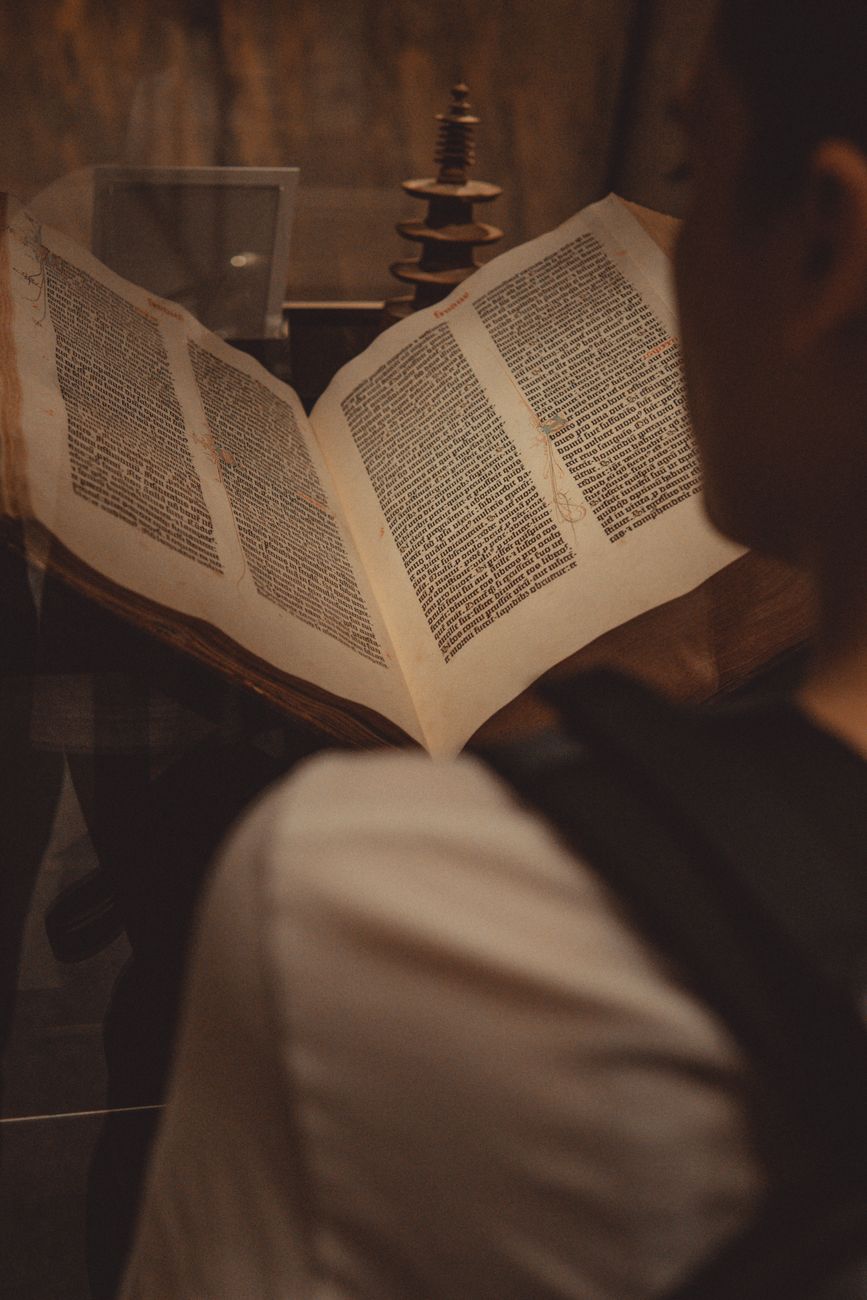 Scholar comparing Bible manuscripts and translation texts at a desk
