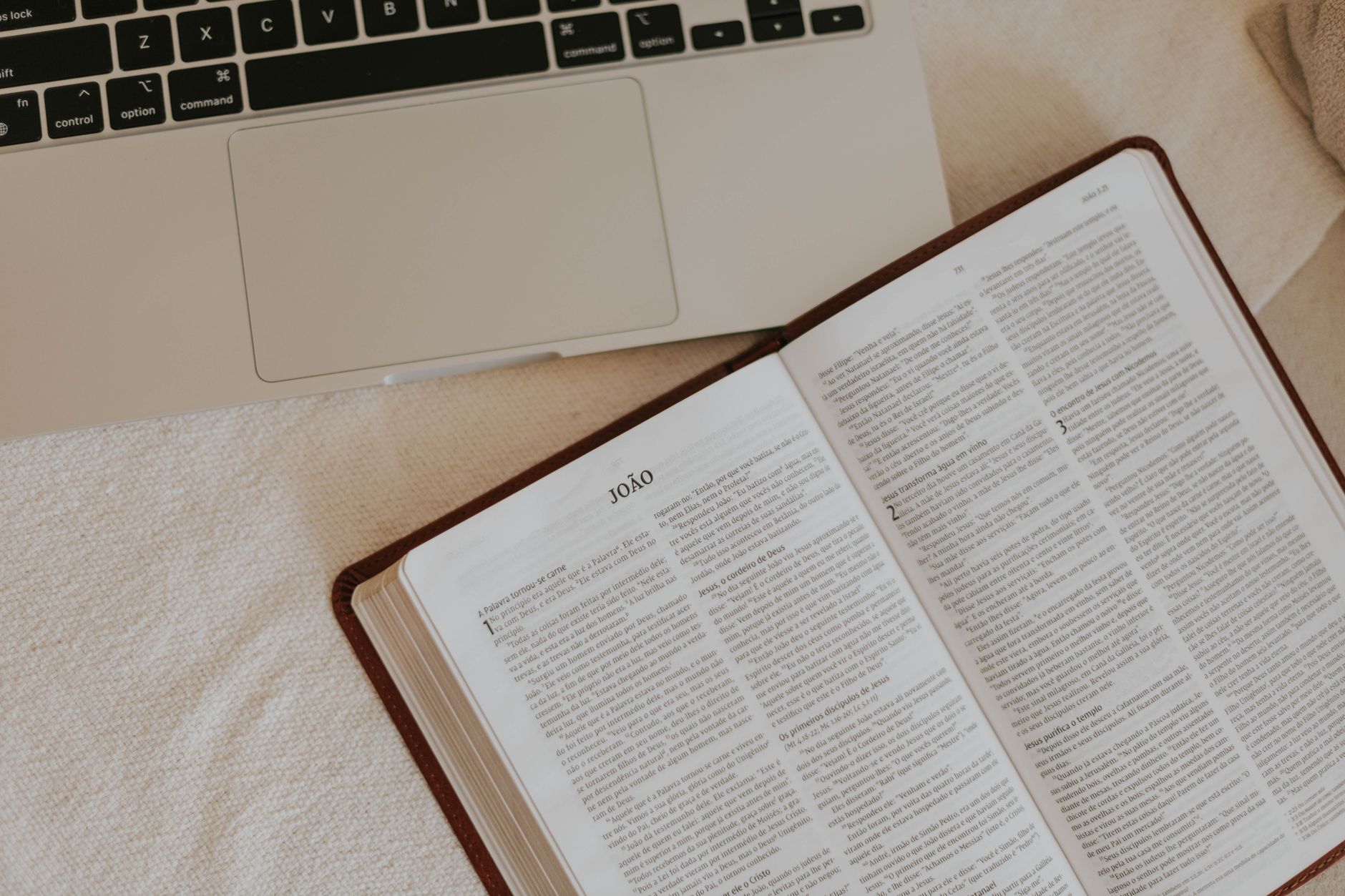 Open Bible with highlighted text and study notes beside a laptop